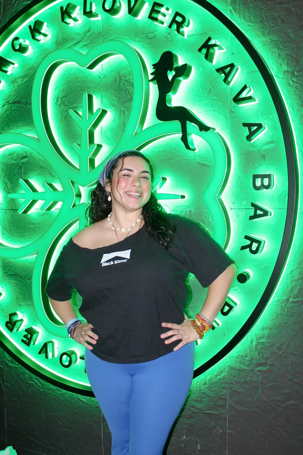 Abigail smiling in front of the Black Klover neon wall