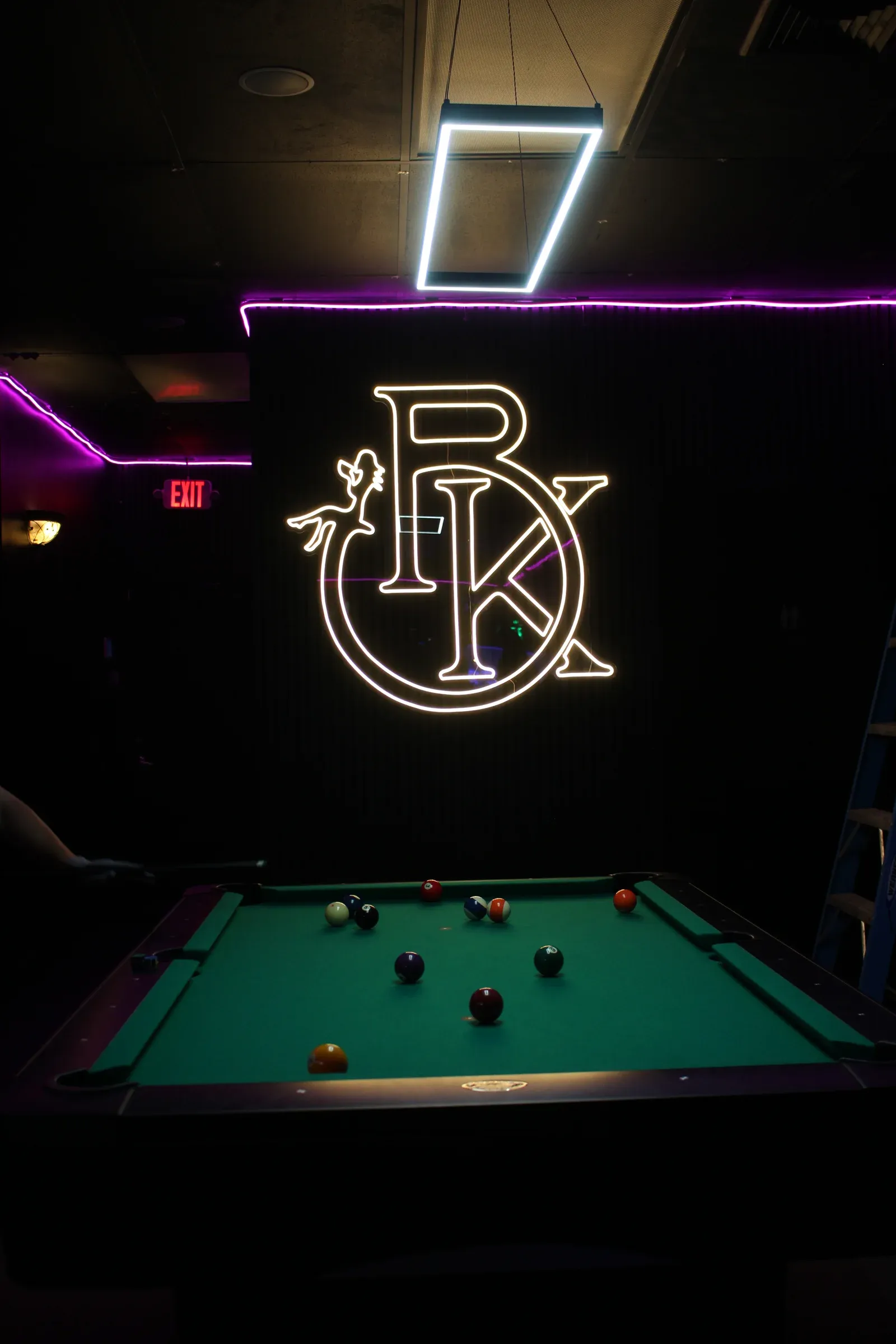 Pool table beneath Black Klover neon signage